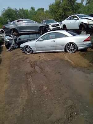A silver car parked in the dirt next to other cars.