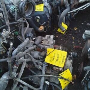 A pile of used car parts with yellow tags on them.