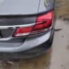 A car is parked in the mud with its lights on.