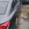 A car parked in the mud next to another car.