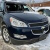 A blue chevy traverse parked in the snow.