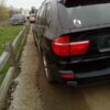 A black car is parked on the side of a road.
