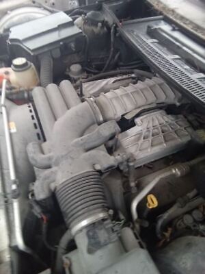 A car engine with the hood open and the air filter on top.