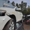 A white car that has been smashed in front of other cars.