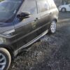 A black car parked on top of gravel.