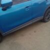A blue car parked on the side of a road.