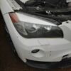 A white car with its hood up and the front end broken.