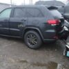 A black jeep parked in the rain with other vehicles.