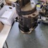 A motor is sitting on the floor next to some other parts.
