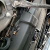 A car engine with the hood open and some parts missing.