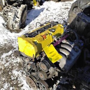 A yellow engine sitting in the snow next to other engines.