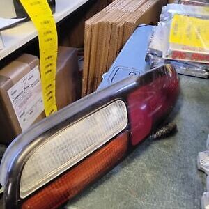 A red and silver car tail light sitting on the floor.