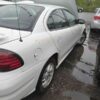 A white car parked in the rain next to another car.