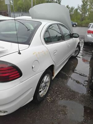 A white car parked in the rain next to another car.