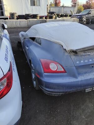 A blue car with the hood up in an alley.