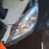 A car 's headlight is broken and has been repaired.