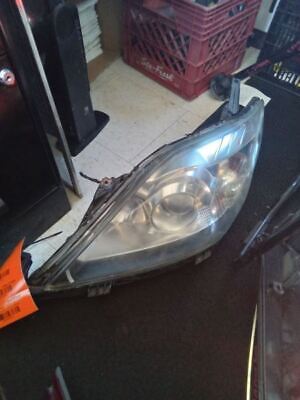 A car headlight that is broken and sitting on the floor.