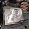 A silver metal box with two headlights on top of it.