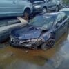 A car that is in the water on the side of the road.
