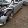 A silver car that has been wrecked in the mud.