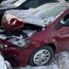 A red car that has been smashed in the snow.