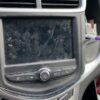 A car dashboard with a dirty screen and some debris on it.