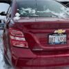 A red car with some broken windows on the back