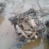 A car engine sitting in the mud of a flooded street.