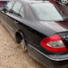 A black car parked on top of a dirt field.