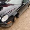A black car is parked in the mud.
