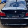 A black bmw parked in the dirt with two cars.