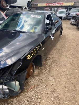 A black car that has been smashed in the middle of the road.