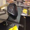 A black chair in front of a rack with boxes.