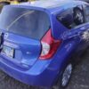 A blue car parked in the dirt with its door open.