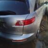 A silver car parked in the mud with its rear lights on.