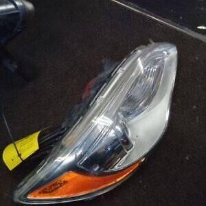 A car headlight with the hood up and a yellow piece of plastic.