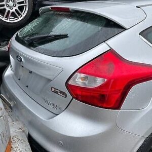 A silver car parked in the street with other cars.