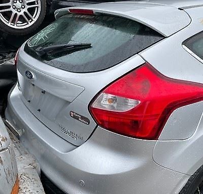 A silver car parked in the street with other cars.