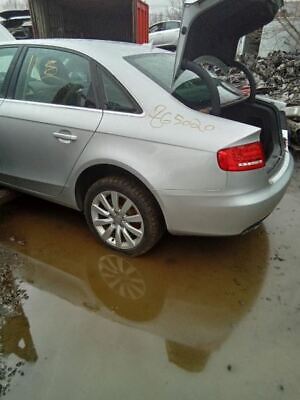 A silver car parked in the mud with its hood up.