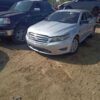 A silver car parked in the dirt next to other cars.