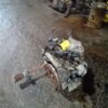 A car engine sitting on the ground in a garage.