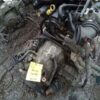 A car engine with many parts on the floor