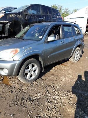 A silver suv parked in the dirt near some other vehicles.
