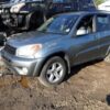 A silver suv parked in the dirt near other vehicles.