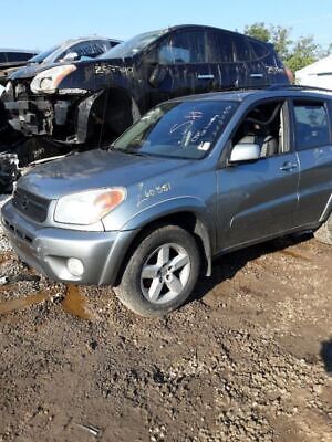 A silver suv parked in the dirt near other vehicles.
