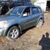 A silver car parked in the dirt near some other cars.