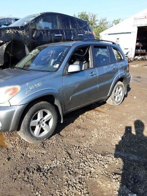 A silver car parked in the dirt near some other cars.