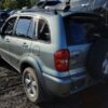 A silver suv with its trunk open parked in the dirt.