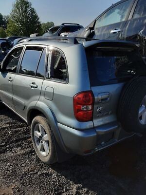 A silver suv with its trunk open parked in the dirt.
