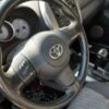 A steering wheel of a car with the dashboard turned on.